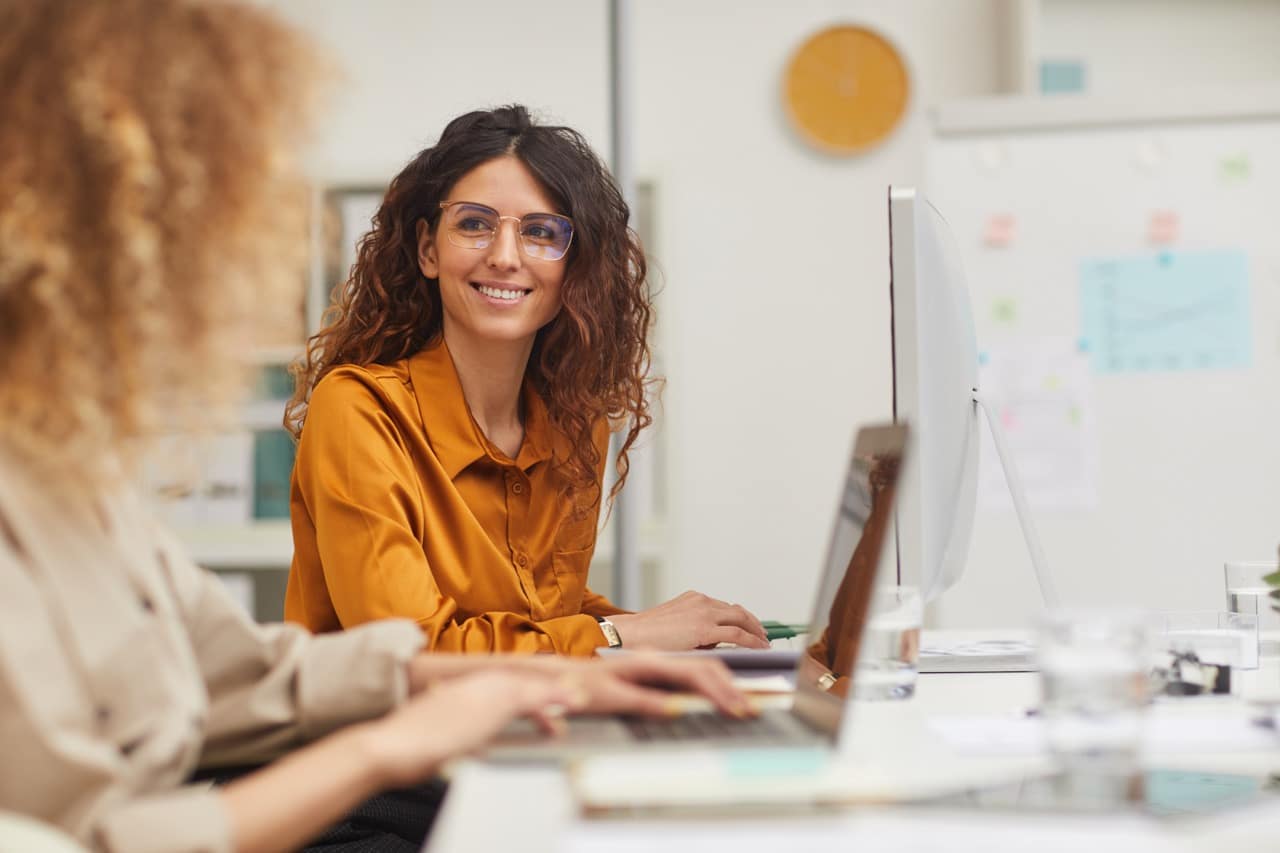 Customer service colleagues working at laptops in a bright office