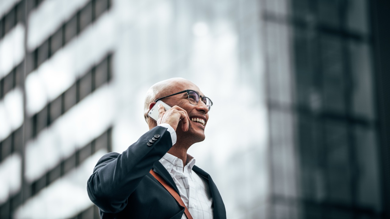 Man smiling while taking a phone call outside a civic building