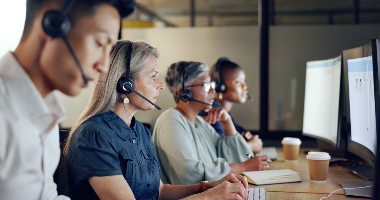 Row of contact centre agents wearing headsets at their workstations