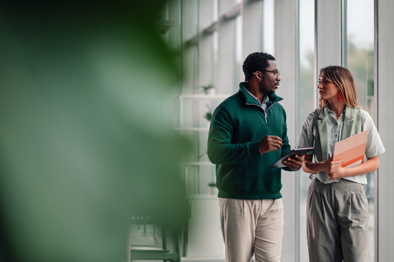 Two colleagues talking over a tablet in a light-filled atrium
