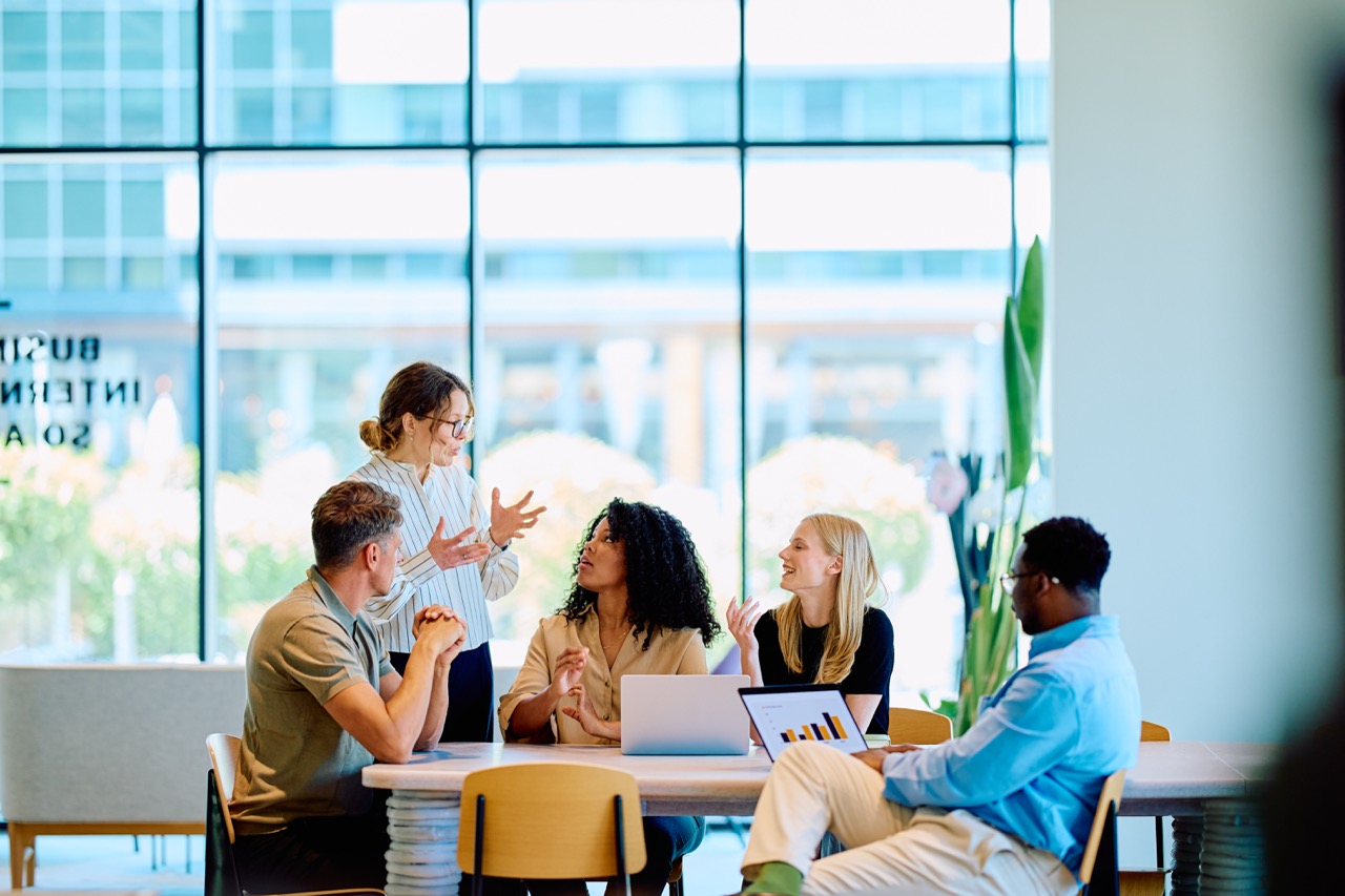 Team meeting around a table in a bright office with floor-to-ceiling windows