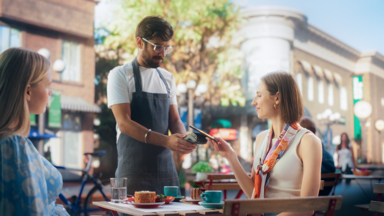 Customer paying by card at an outdoor cafe table
