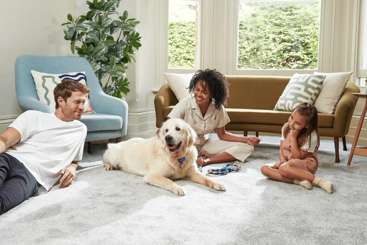 Family relaxing on a living room floor with their dog