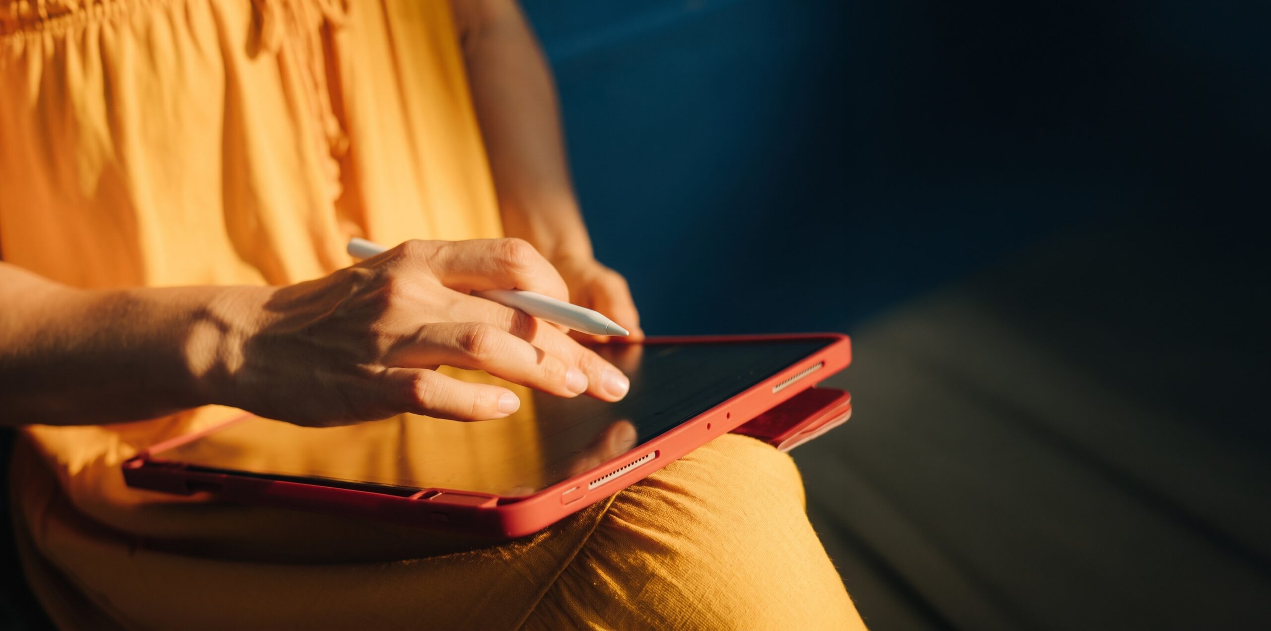 Person in a yellow top using a stylus on a tablet