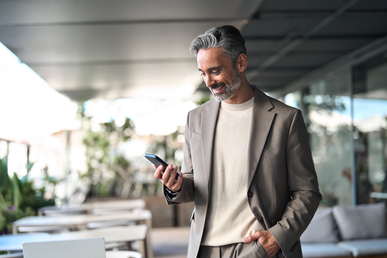 Traveller smiling at his phone in an airport lounge