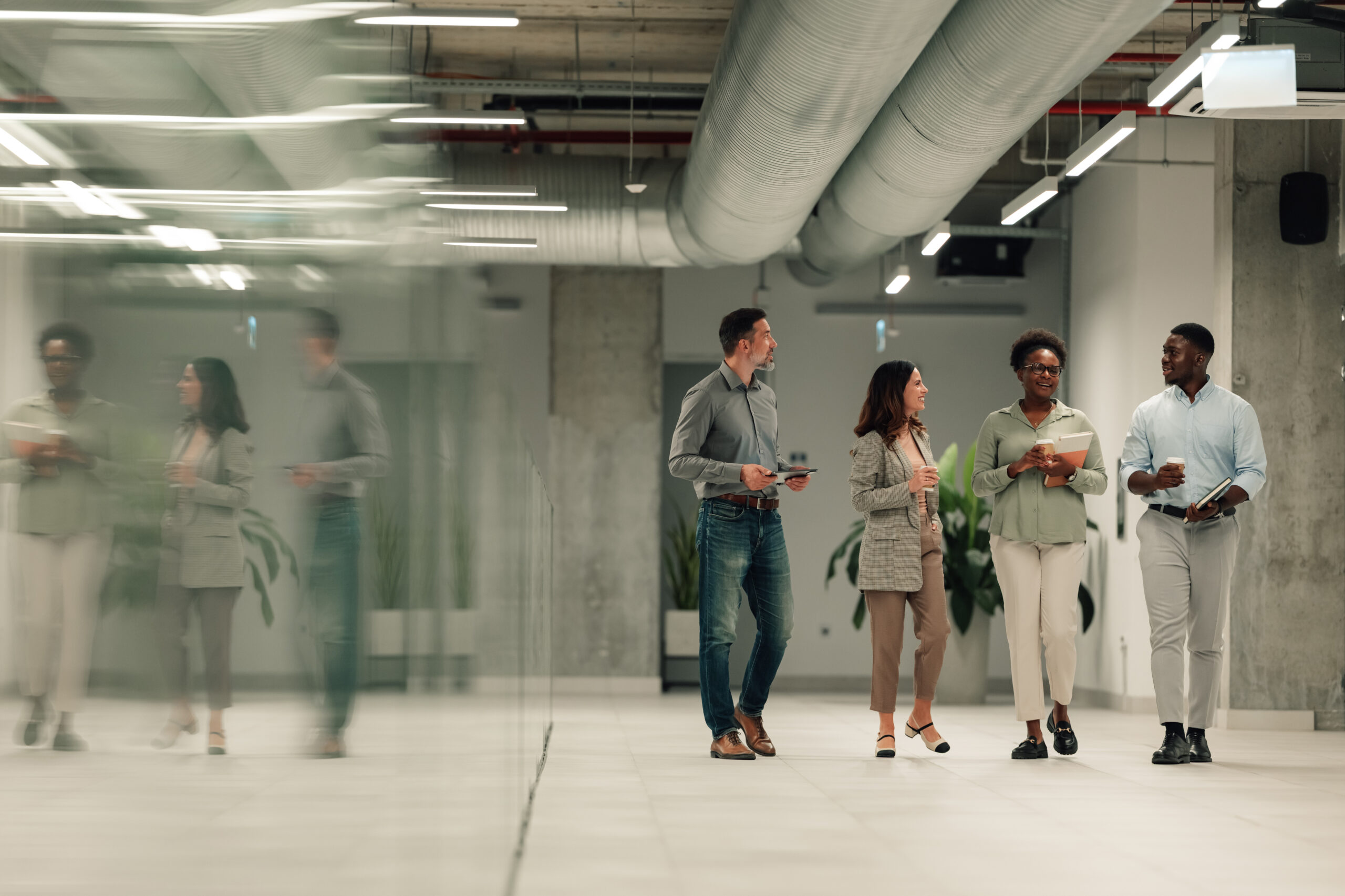 Group of colleagues walking and talking through a bright office atrium