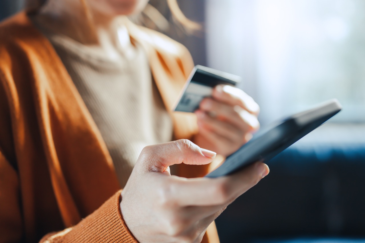 Customer holding a payment card while tapping on a tablet