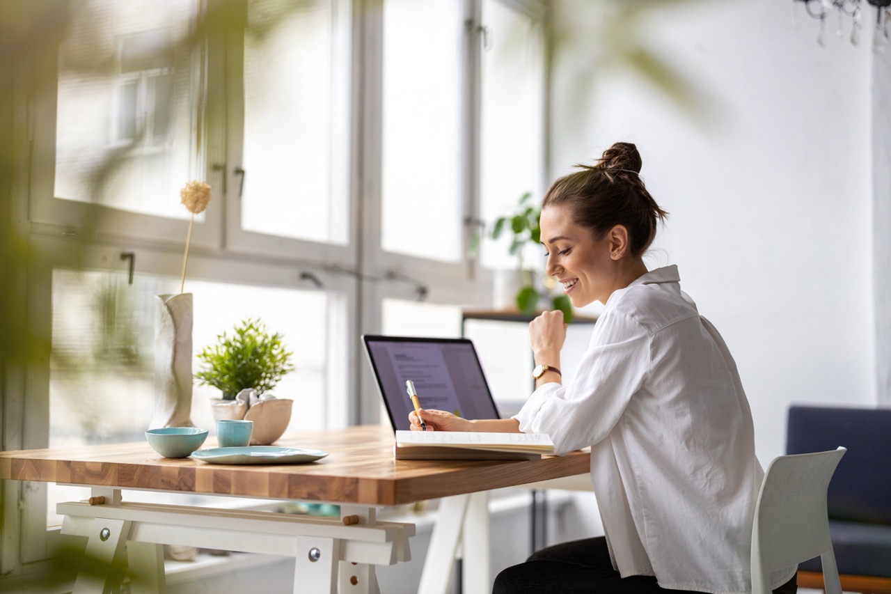 Person working at a laptop beside a sunlit window
