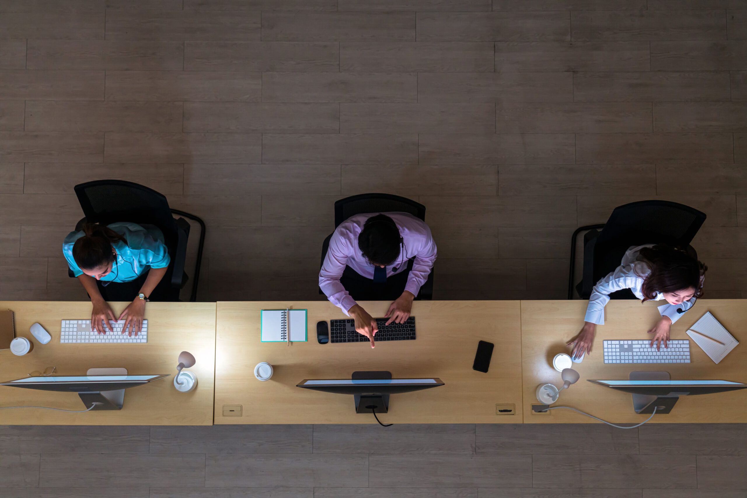 Overhead view of a contact centre team working at a long shared desk