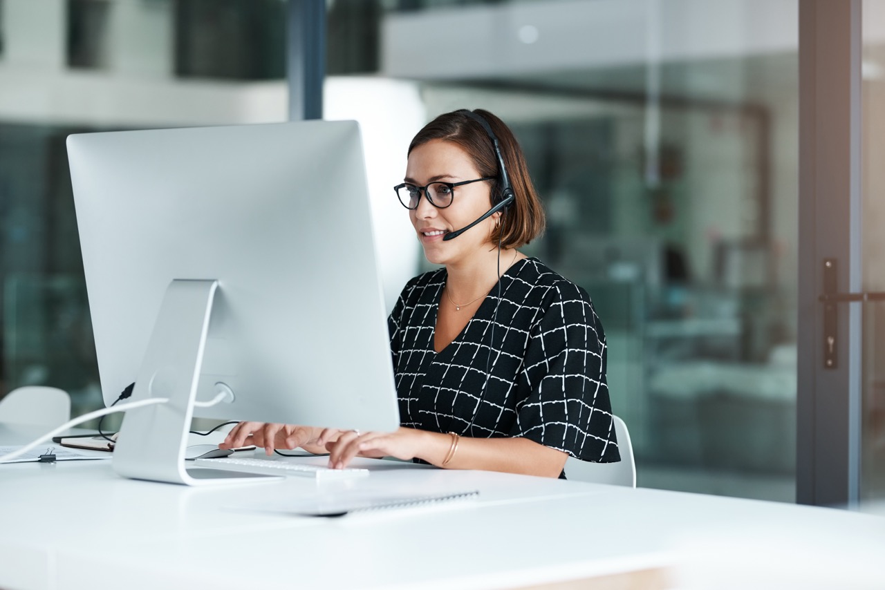 Customer service agent working at a desktop computer wearing a headset
