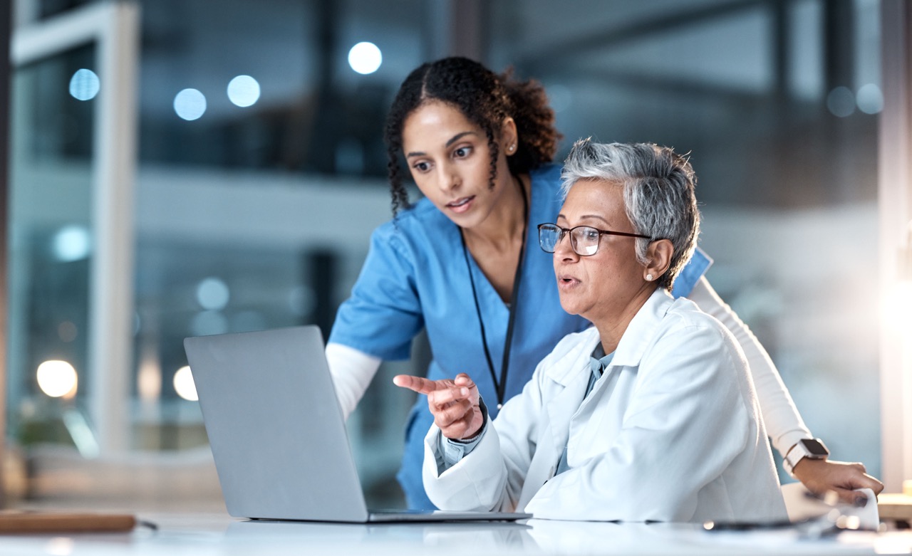 Two healthcare colleagues reviewing information together on a laptop